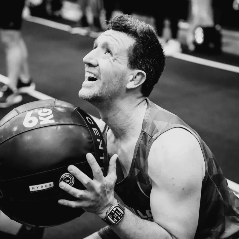 Man squats holding 6kg Wall ball at HYROX Event